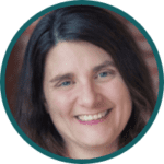 A woman with long dark brown hair is smiling at the camera. She appears to be in an indoor setting with a blurred background. The image is framed in a circular border.