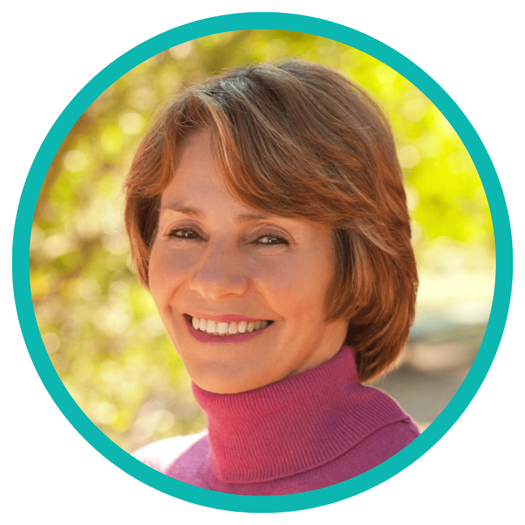 A person with short brown hair is smiling outdoors. They are wearing a pink turtleneck sweater. The background is bright and blurred with green and yellow hues. The image has a turquoise circular border. A person with short brown hair is smiling outdoors. They are wearing a pink turtleneck sweater. The background is bright and blurred with green and yellow hues. The image has a turquoise circular border.