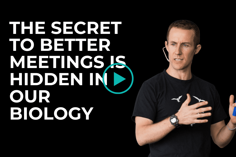 A man wearing a headset and black shirt gestures while speaking. Large text on the left reads, "The secret to better meetings is hidden in our biology." A play button icon is overlaid in the center. A man wearing a headset and black shirt gestures while speaking. Large text on the left reads, "The secret to better meetings is hidden in our biology." A play button icon is overlaid in the center.